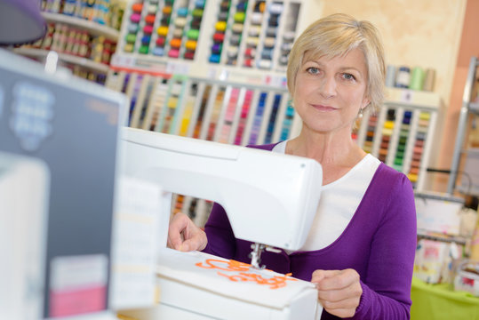 smiley woman sewing on sewing-machine