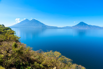 Naklejka na ściany i meble View from Lake Atitlan in the early morning, blue skys and clear water, beautiful magic lake with volcanos and indigenous people in the highland of Guatemala 