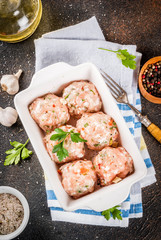 Raw homemade chicken or turkey meatballs in baking dish dark rusty background. Copy space