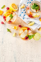 Summer cold cocktail, fruit and berry white sangria with apple, lemon, oranges and raspberry. light concrete background, copy space top view