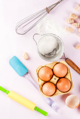 Fototapeta na wymiar Ingredients and utensils for cooking baking egg, flour, sugar, whisk, rolling pin, on light pink background, top view