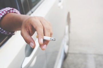 close up hand smoking a cigarette in car.
