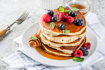Healthy summer breakfast,homemade classic american pancakes with fresh berry and honey, morning light grey stone background copy space