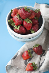 Blue daisies with red juicy strawberries on a blue wooden background