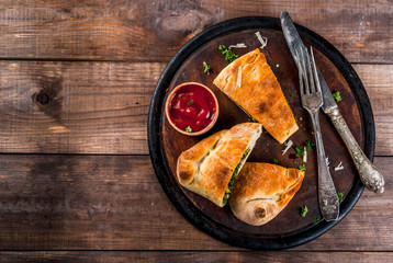 Italian food, closed pizza calzone with Spinach and Cheese, wooden background, copy space top view