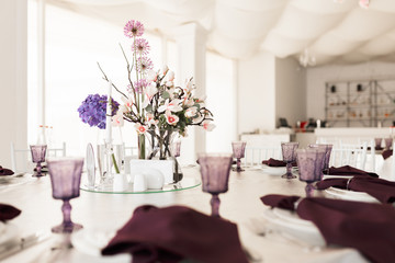 Close up photo of beautiful table setting and bouqet in center at wedding hall isolated