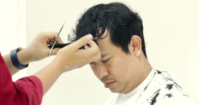 Asian Man getting a haircut by a hairdresser.