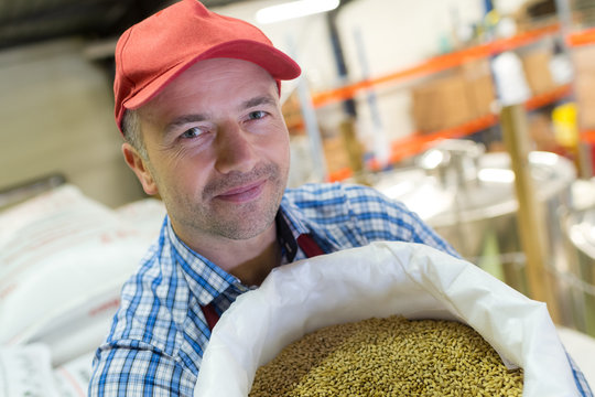 handsome mature worker holding bag of malt