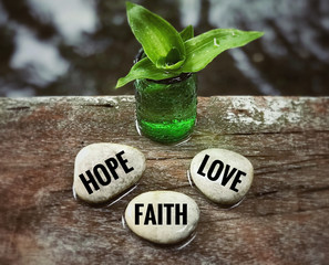 Religion and belief concept - ‘Hope, faith and love’ words on white pebbles. With blurred vintage styled background. - Powered by Adobe