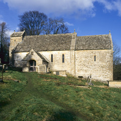 Fototapeta na wymiar Winter sunshine on the tiny old Saxon church at Duntisbourne Rouse in the Cotswolds, Gloucestershire, UK