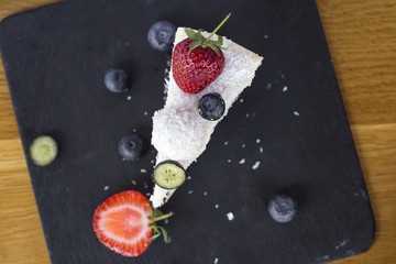 Delicious Chocolate Cake made with white and dark chocolate, fruits and coconut on slate