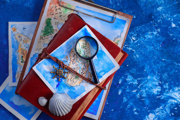 Sea travel and painting concept. Watercolor fantasy map on leather cover captain journals with a magnifying glass on a navy blue background with copy space.