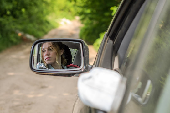 Reflection of a girl sitting in the car in a car mirror