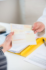 Close-up of the hand of a female patient receiving a printed medical prescription from the primary care  physician