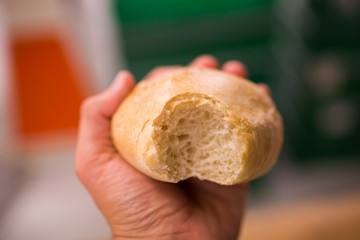 White hand holding bread bun bite