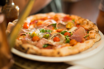 Closeup ham prosciutto tomato mozzarella italian pizza