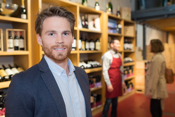 Obraz premium smiling man choosing bottle of wine in shop