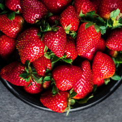 Strawberry. Fresh strawberry on black background with copy space for text. Heap of Red strewberry on a plate close up.