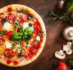 Hot pizza with Pepperoni  with vegetables and fresh ingredients on rustic wooden table. Pizza menu. View from above.