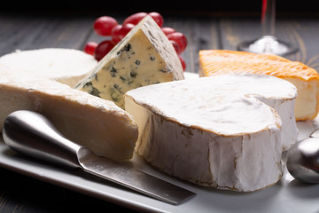 French cheeses plate in assortment, blue cheese, brie, munster, soft goat cheese, Neufchatel heart shaped cheese