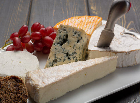 French cheeses plate in assortment, blue cheese, brie, munster, soft goat cheese, Neufchatel heart shaped cheese