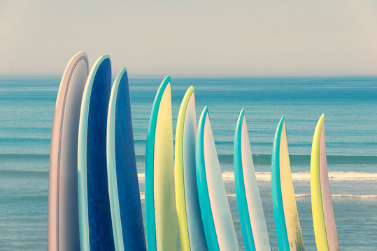 Stack of colorful surfboads on ocean background with waves, retro vintage filter
