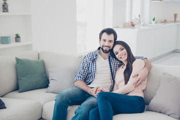 Portrait of stylish trendy couple spending time together indoor, in flat, apartment sitting on sofa looking at camera. True feelings affection idyllic harmony concept