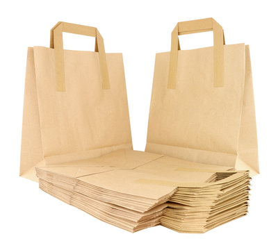 Group of folded and unfolded plain brown paper take away food carrier bags with handles isolated on a white background