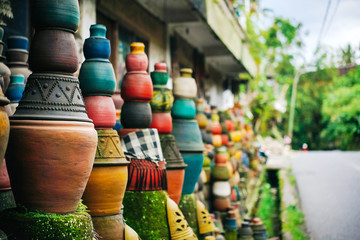 Fototapeta premium Many multicolored traditional clay pots standing near the wall. Asia, Bali.
