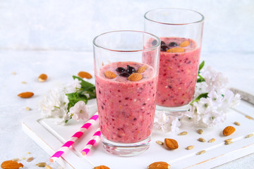 Blueberry smoothies of berries, banana and almonds in glasses with cocktail tubes on a white wooden board.