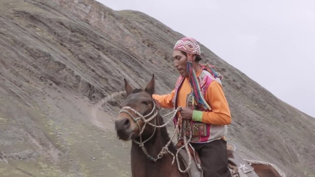 Peruvian man wears a traditional Peruvian costume and riding horse on the mountains of Peru. Slow motion
