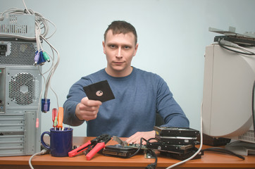 Hacker is holding in one hand a diskette disk with secret information data.