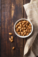 Almonds in a bowl. Brown background.