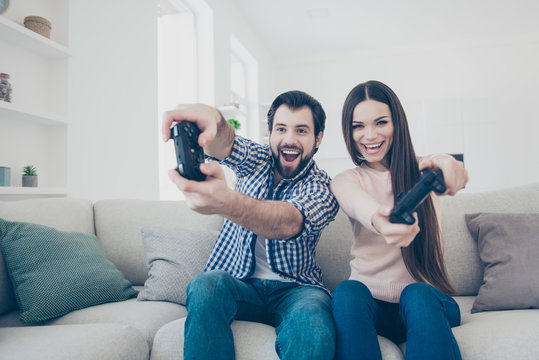 Portrait of crazy playful couple enjoying playing videogame on playstation indoor, holding console gamepad in hands, fans of xbox