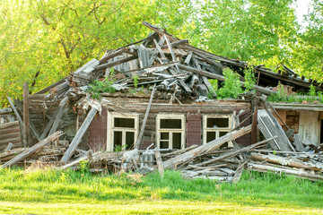 facade of the abandoned destroyed wooden house with three windows with broken glass