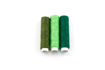 Different green cotton yarns on rolls for sewing