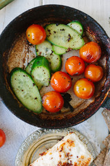 Fresh and ripe vegetables - tomatoes and cucumbers, roasted on fry pan.