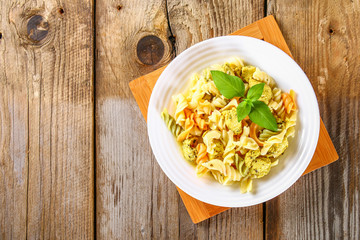 Pasta with slices of fried chicken fillet on an old wooden table.