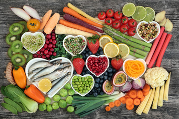 Concept de super aliment sain avec du poisson frais, des légumes et des fruits dans des plats en forme de coeur et en vrac. Aliments santé riches en oméga 3, antioxydants, anthocyanes, minéraux, vitamines, vue de dessus.