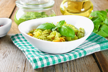 Pasta with pesto sauce on an old wooden table.