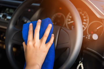 Close-Up of Woman Hand is Cleaning Car Steering Wheel With Cleaner Microfiber Cloth, Car Washing and Vehicle Maintenance Service. Business Cars Wash and Transportation Automotive Equipment