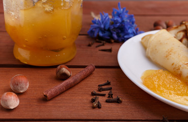 tasty home made pancakes with honey on craft wood table decorated with nuts, cinnamon and carnation