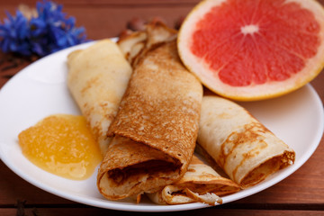 tasty home made pancakes with honey on craft wood table decorated with nuts, cinnamon and carnation