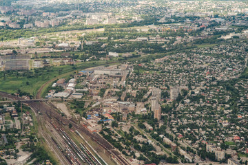 Aerial picture of city with houses and gardens, crossroads and roads, houses, buildings, parks and parking lots, bridges. Airplane drone shot.