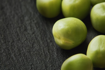 Fresh raw green peas on black rustic background. Copy space