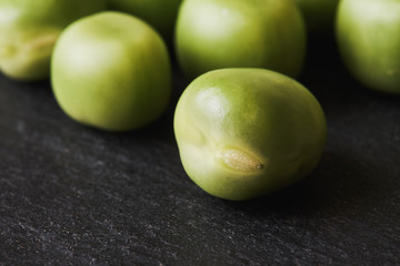 Fresh raw green peas on black rustic background