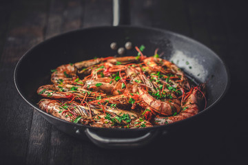 Shrimps fried in a pan. Classic recipe - parsley, garlic, chilli peppers and white wine.