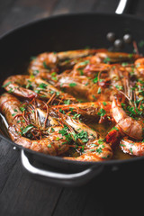 Shrimps fried in a pan. Classic recipe - parsley, garlic, chilli peppers and white wine.