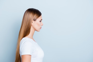 Fototapeta premium Advertisement concept. Portrait with copyspace empty place for product of serious calm girl with long hair in white t-shirt isolated on grey background