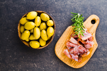 Prosciutto with rosemary on a black background.